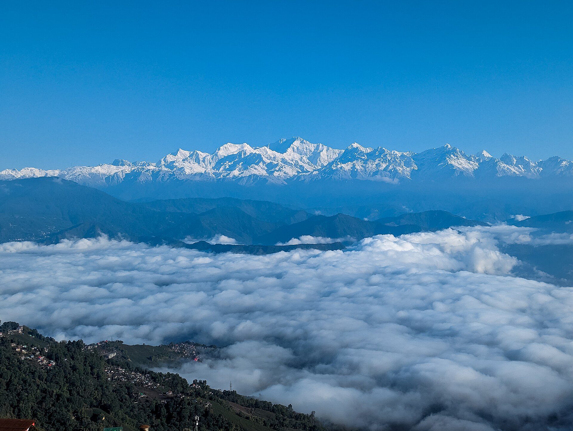 Darjeeling hill ridge rising above a sea of white valley clouds with the snow-covered Kangchenjunga range on the horizon