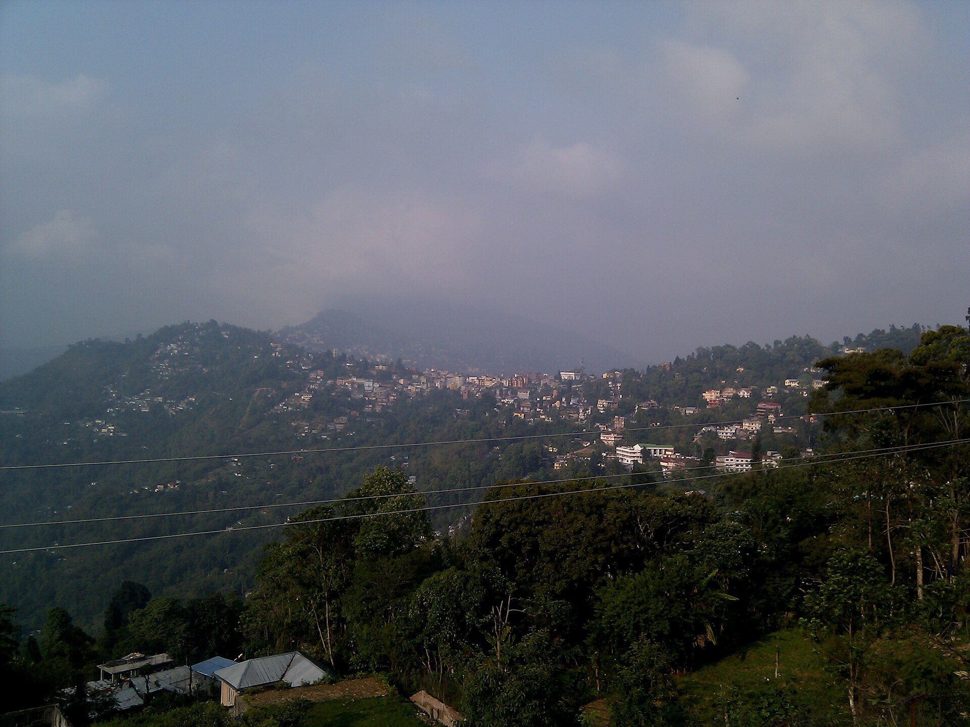 Kalimpong town spread across forested ridges under soft mountain clouds