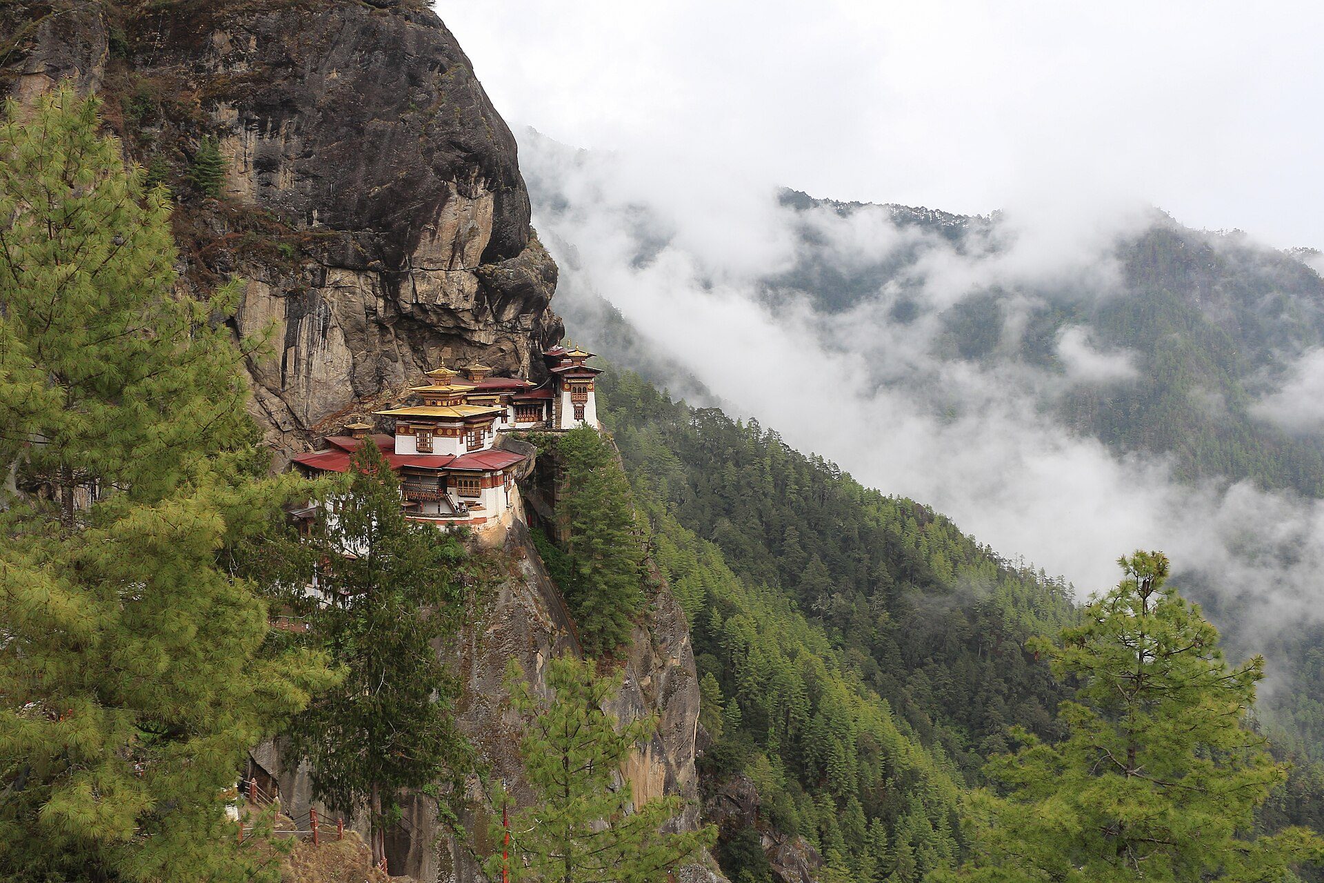 Paro Taktsang (Tiger's Nest Monastery) clinging to a sheer granite cliff amidst drifting mountain clouds in Paro Valley, Bhutan