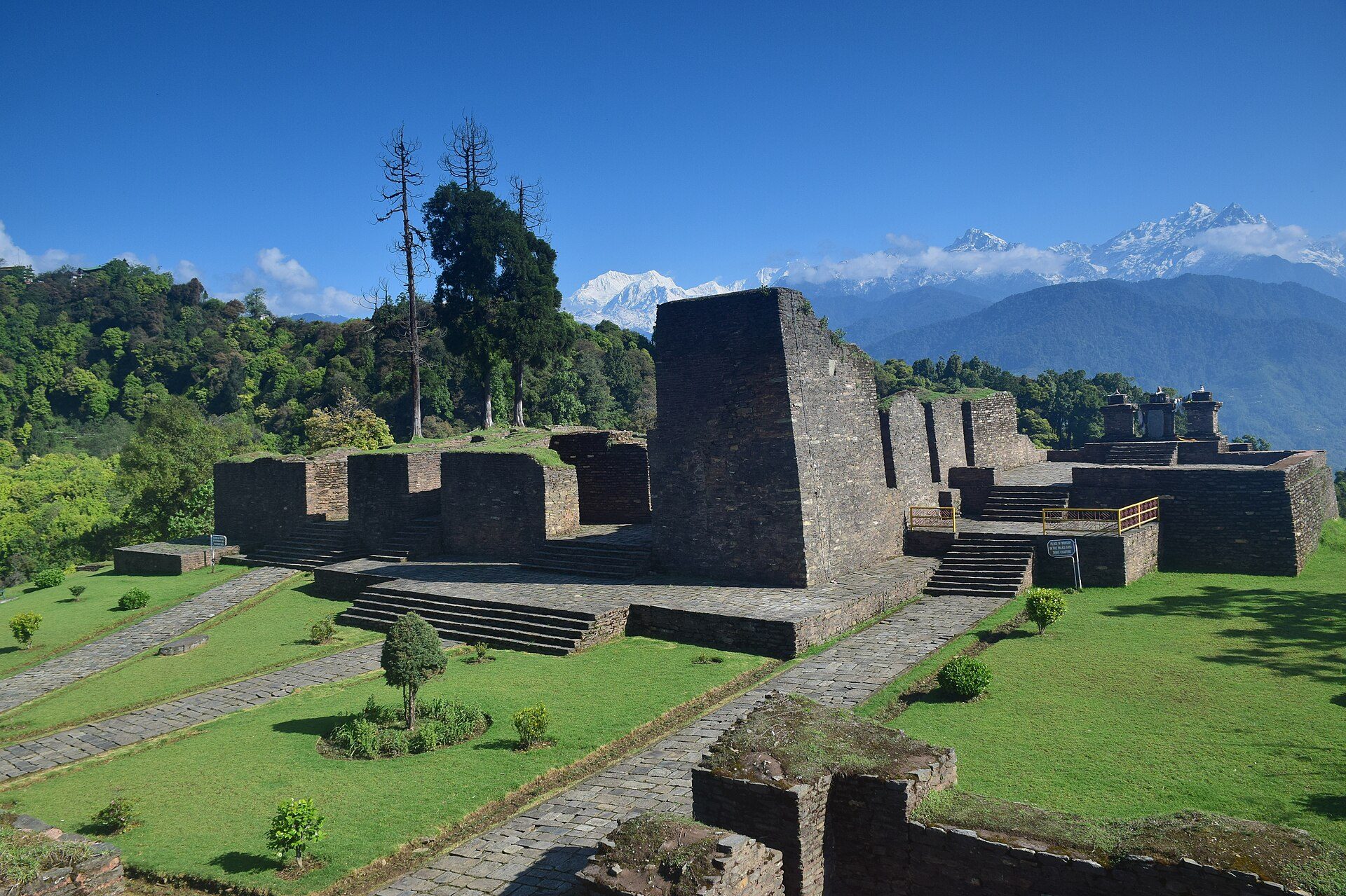 Stone palace ruins of Rabdentse at Pelling surrounded by green forest with the snow peaks of Kangchenjunga in the distance