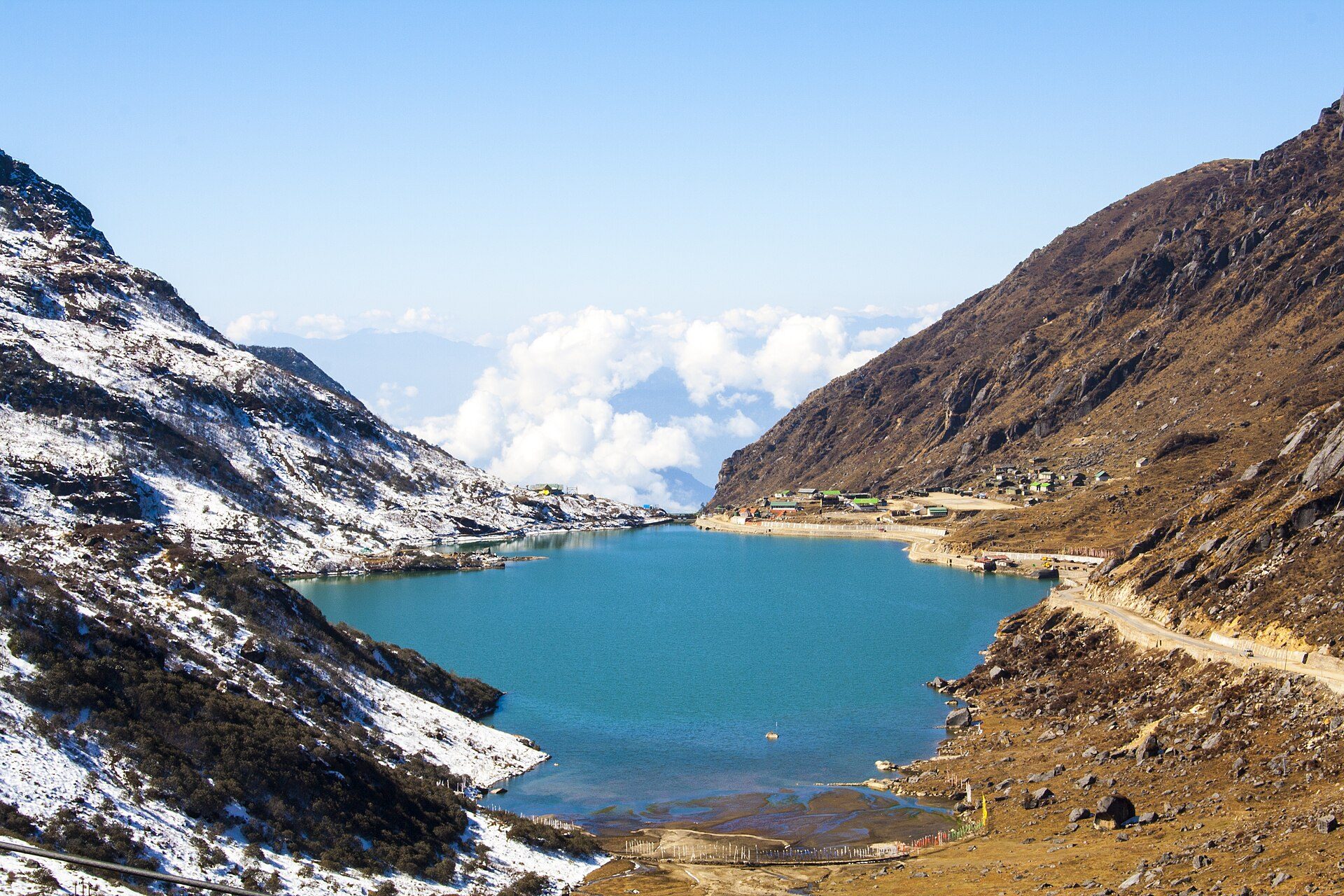 Glacial turquoise waters of Tsomgo Lake nestled between steep snow-dusted ridges in East Sikkim